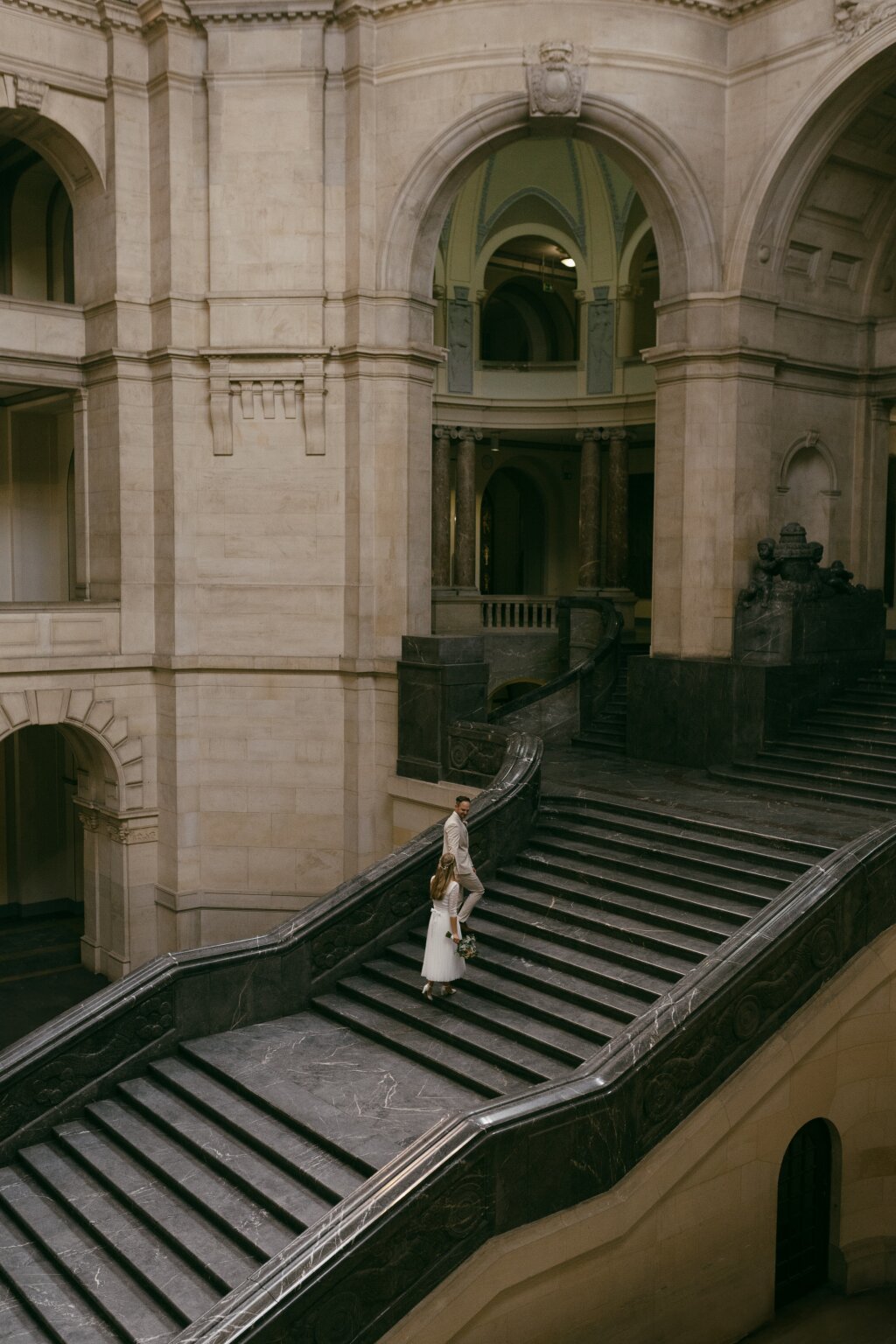 Brautpaar im Alten Rathaus in Hannover das sie Treppe hinauf geht.