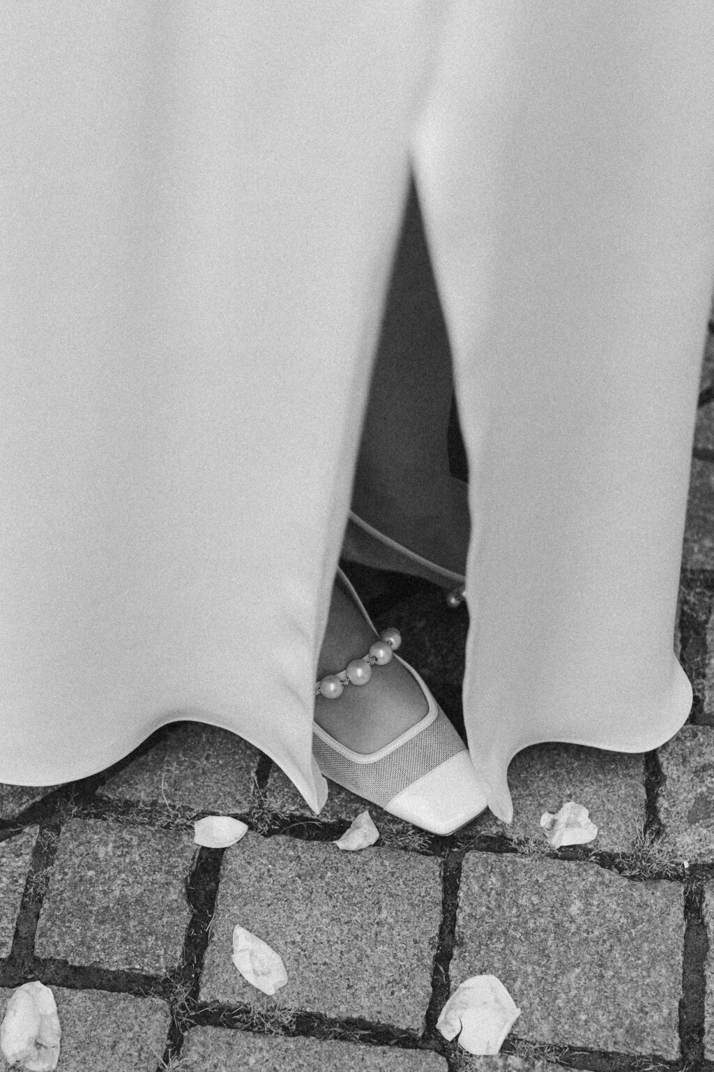 Jimmy Choo Schuhe mit Perlen, daneben Blütenblätter.